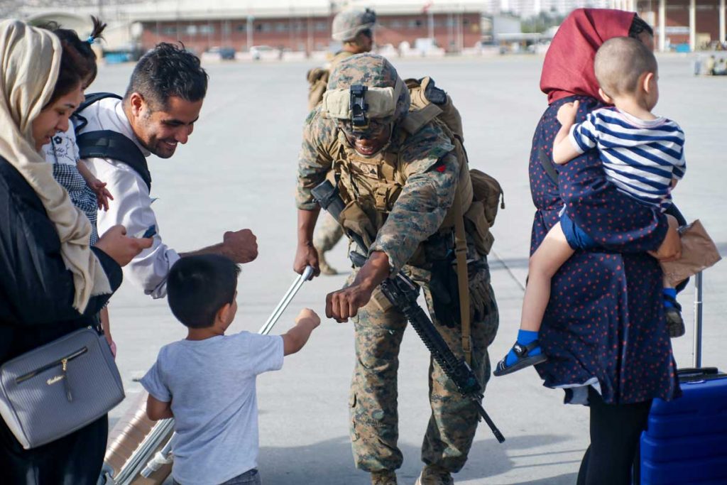 A US Marine fist bumps an Afghan Child as the family awaits processing
