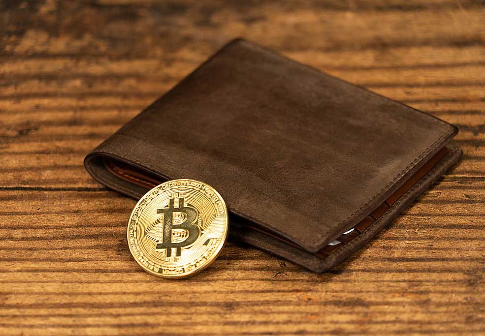 Bitcoin represented as a gold coin next to a wallet