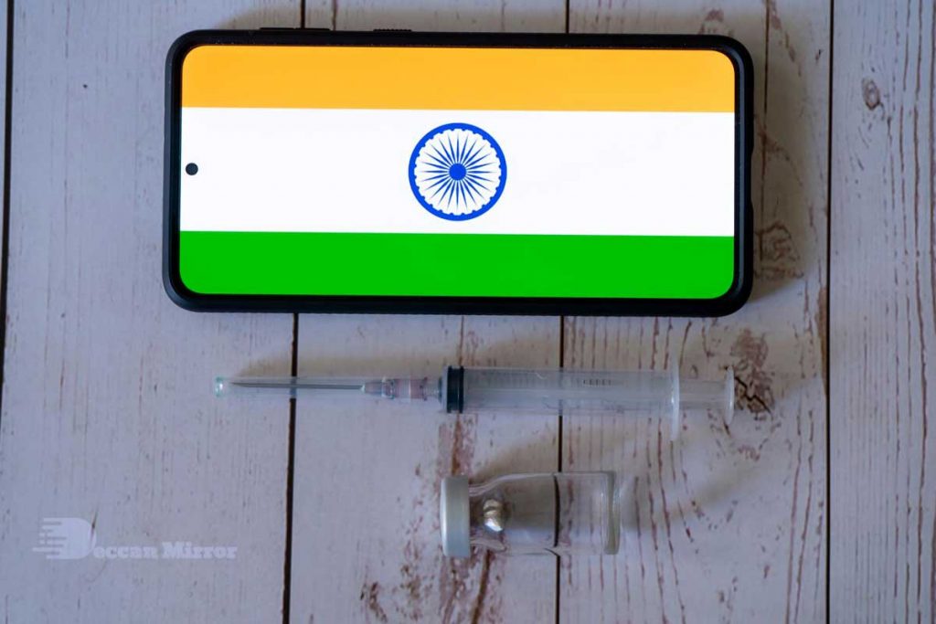 Indian Flag is seen in a mobile phone as a vaccination syringe lies nearby.