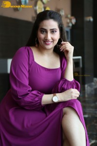 Anchor Manjusha in a purple dress posing for pictures