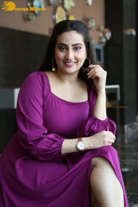 Anchor Manjusha in a purple dress posing for pictures