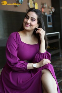 Anchor Manjusha in a purple dress posing for pictures