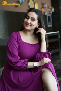 Anchor Manjusha in a purple dress posing for pictures