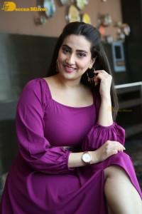 Anchor Manjusha in a purple dress posing for pictures