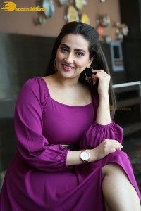 Anchor Manjusha in a purple dress posing for pictures