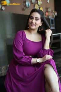 Anchor Manjusha in a purple dress posing for pictures