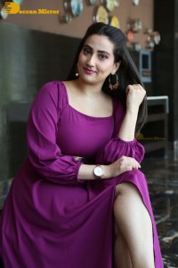Anchor Manjusha in a purple dress posing for pictures