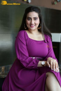 Anchor Manjusha in a purple dress posing for pictures