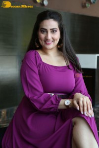 Anchor Manjusha in a purple dress posing for pictures