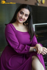 Anchor Manjusha in a purple dress posing for pictures