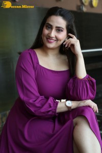 Anchor Manjusha in a purple dress posing for pictures