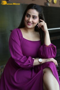 Anchor Manjusha in a purple dress posing for pictures