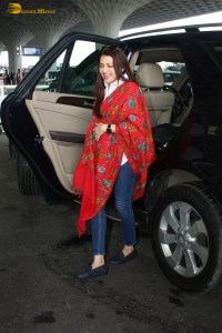 actress Bhagyashree in a white shirt and red shawl looking classy at the airport