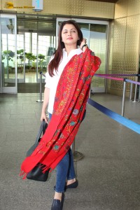 actress Bhagyashree in a white shirt and red shawl looking classy at the airport