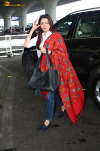 actress Bhagyashree in a white shirt and red shawl looking classy at the airport