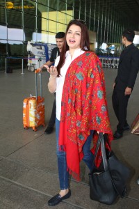 actress Bhagyashree in a white shirt and red shawl looking classy at the airport