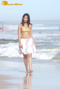 Ileana D’Cruz in a gold top and white skirt walking on the beach