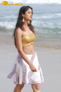 Ileana D’Cruz in a gold top and white skirt walking on the beach