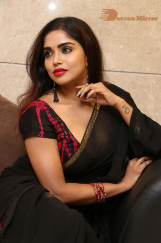 Telugu Actress Karunya Chowdary dressed in a black saree posing for photos