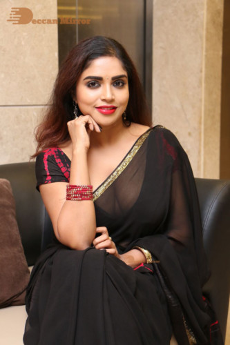 Telugu Actress Karunya Chowdary dressed in a black saree posing for photos