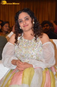 Nithya Menen in a white top and colorful skirt attending a movie function