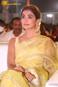 Actress Pooja Hegde in a yellow saree while attending the pre-release event of the Telugu movie Acharya