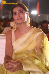 Actress Pooja Hegde in a yellow saree while attending the pre-release event of the Telugu movie Acharya