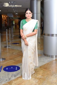 Actress Poorna in a white saree and green blouse posing for a photoshoot