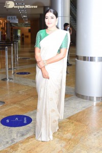 Actress Poorna in a white saree and green blouse posing for a photoshoot