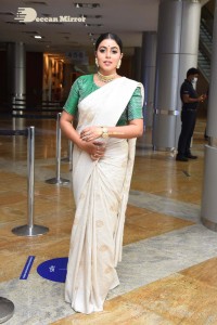 Actress Poorna in a white saree and green blouse posing for a photoshoot