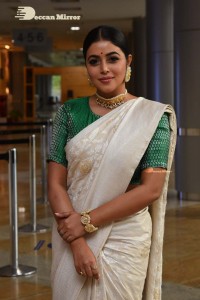 Actress Poorna in a white saree and green blouse posing for a photoshoot