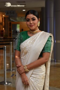 Actress Poorna in a white saree and green blouse posing for a photoshoot