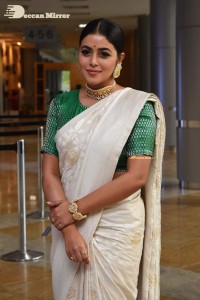 Actress Poorna in a white saree and green blouse posing for a photoshoot