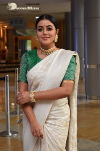 Actress Poorna in a white saree and green blouse posing for a photoshoot