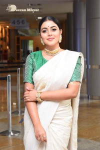 Actress Poorna in a white saree and green blouse posing for a photoshoot