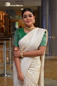 Actress Poorna in a white saree and green blouse posing for a photoshoot