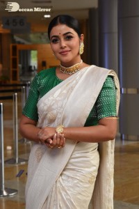 Actress Poorna in a white saree and green blouse posing for a photoshoot