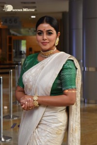 Actress Poorna in a white saree and green blouse posing for a photoshoot