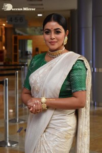 Actress Poorna in a white saree and green blouse posing for a photoshoot