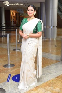 Actress Poorna in a white saree and green blouse posing for a photoshoot