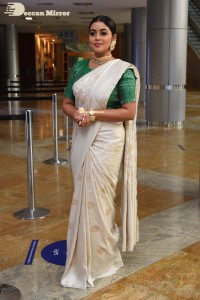 Actress Poorna in a white saree and green blouse posing for a photoshoot