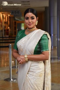 Actress Poorna in a white saree and green blouse posing for a photoshoot