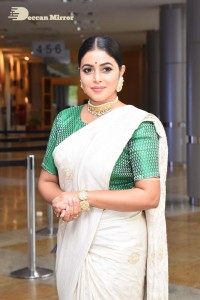 Actress Poorna in a white saree and green blouse posing for a photoshoot