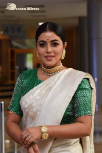 Actress Poorna in a white saree and green blouse posing for a photoshoot