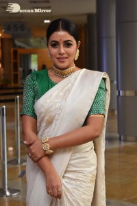Actress Poorna in a white saree and green blouse posing for a photoshoot