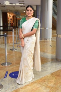 Actress Poorna in a white saree and green blouse posing for a photoshoot