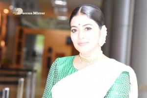 Actress Poorna in a white saree and green blouse posing for a photoshoot