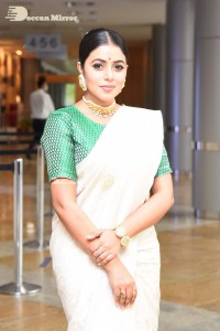Actress Poorna in a white saree and green blouse posing for a photoshoot
