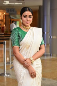 Actress Poorna in a white saree and green blouse posing for a photoshoot
