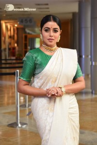 Actress Poorna in a white saree and green blouse posing for a photoshoot